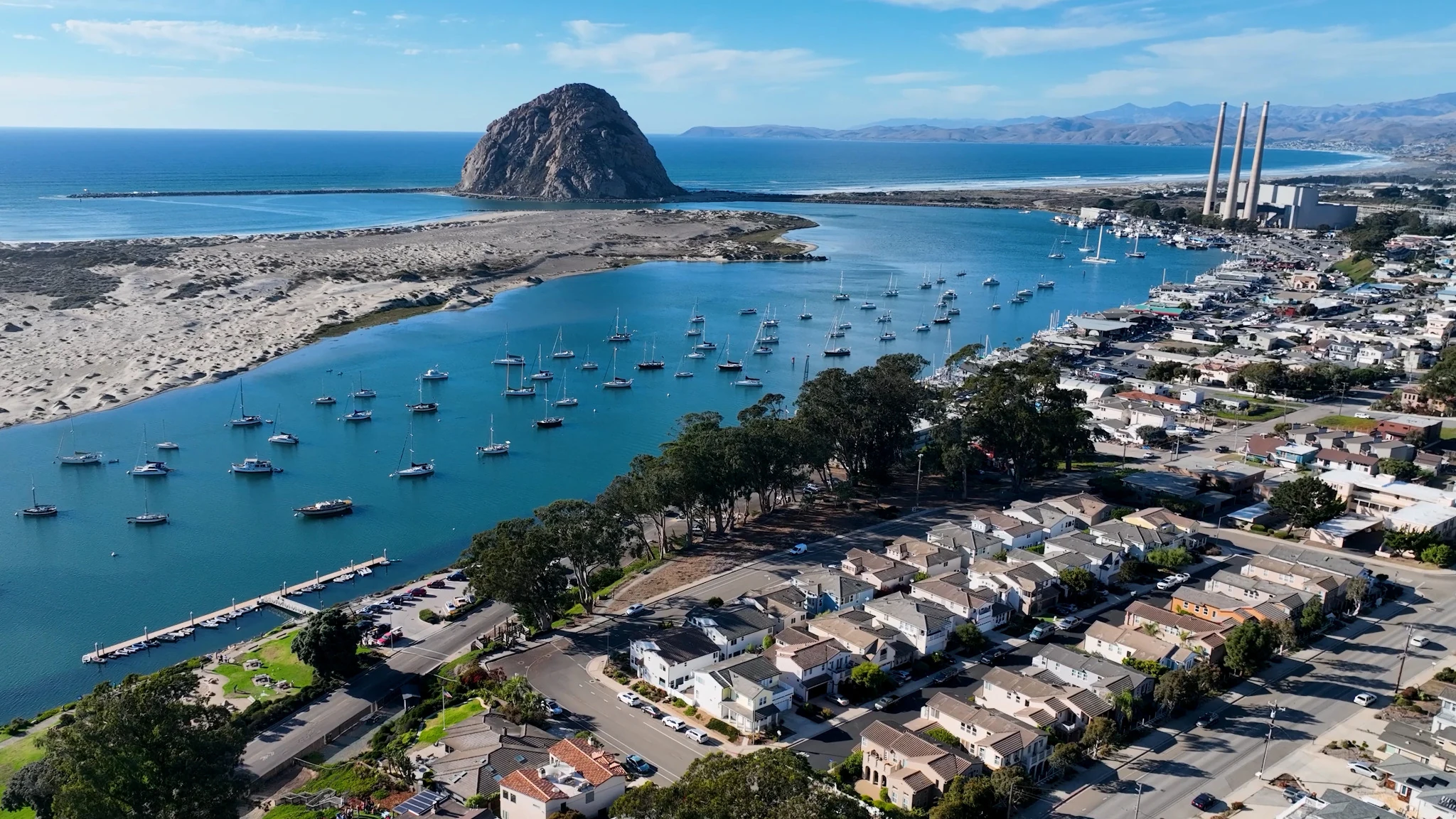 Aerial view of Morro Bay with Morro Rock, the harbor, homes and the three stacks