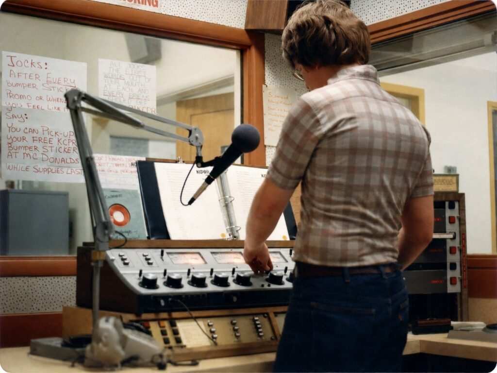 KCPR DJ standing at the radio control board in the Cal Poly studio