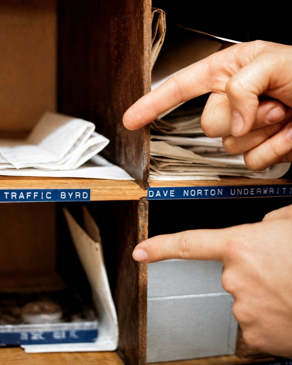 Close-up photo of KCPR station mail cubbies with hands pointing to a slot labeled Traffic Byrd